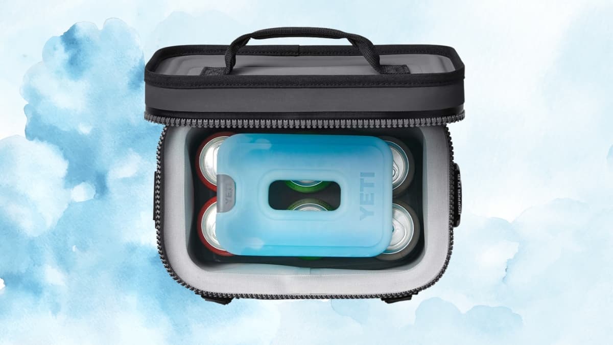 Blue YETI ICE sheet placed on top of canned drinks inside a soft-sided cooler bag.