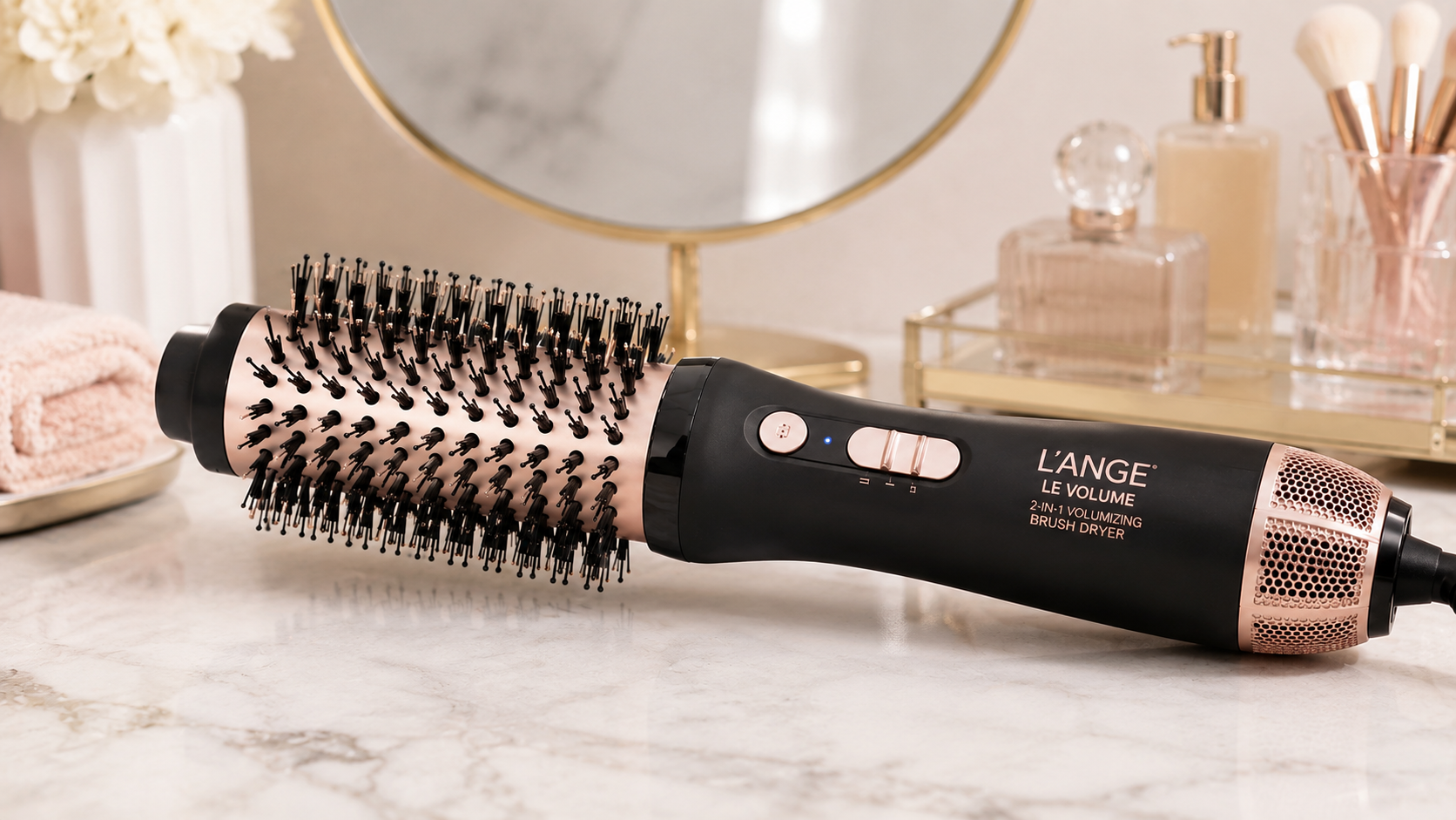L’ange Le Volume 2-in-1 Volumizing Brush Dryer in black and rose gold on a marble vanity countertop with luxury bathroom decor and soft natural lighting.