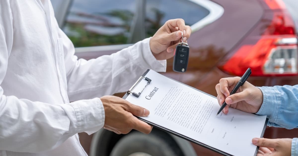 Customer signing car rental contract while receiving vehicle keys at pickup location