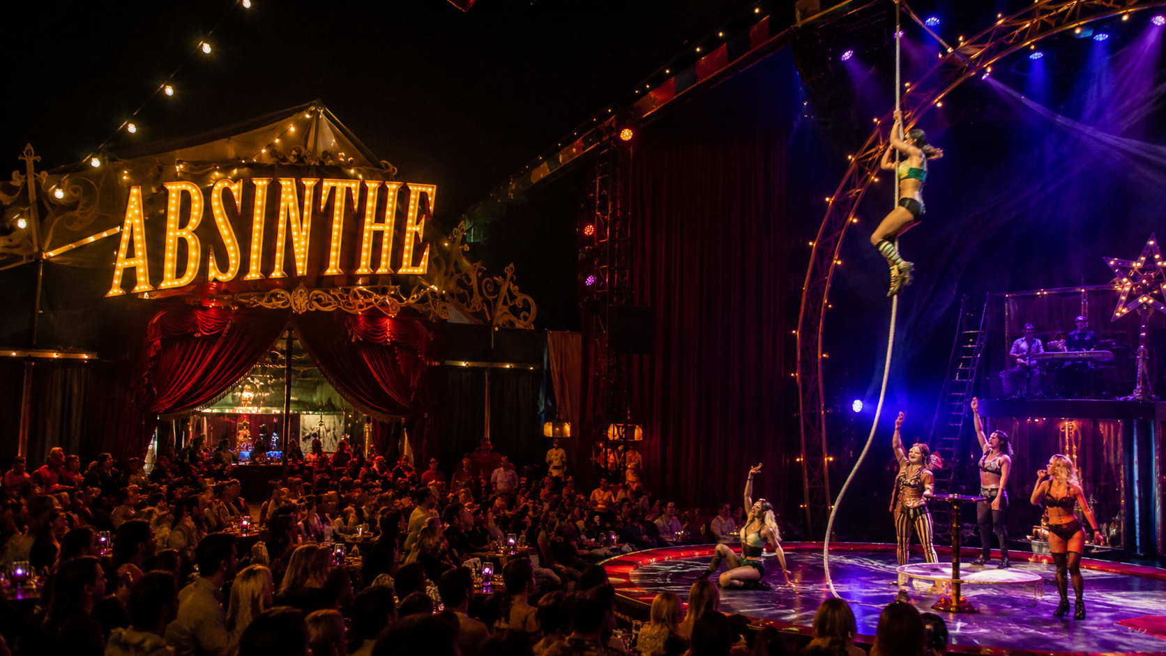 Audience watching the ABSINTHE Las Vegas circus and cabaret show featuring aerial acrobats, comedy, and live entertainment inside the Spiegelworld tent at Caesars Palace.